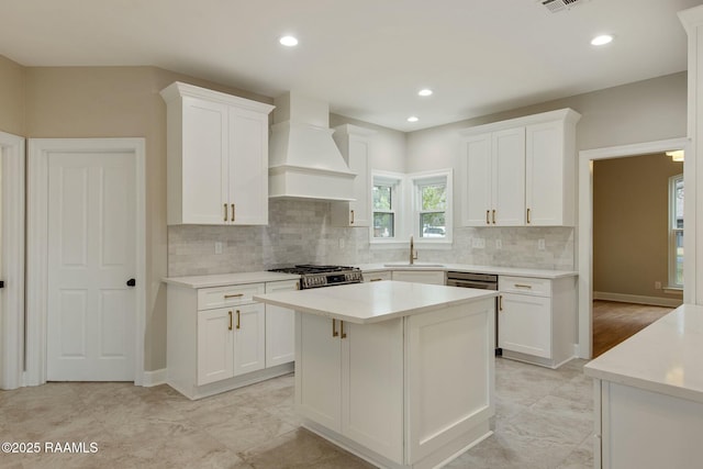 kitchen featuring white cabinets, custom range hood, and a sink