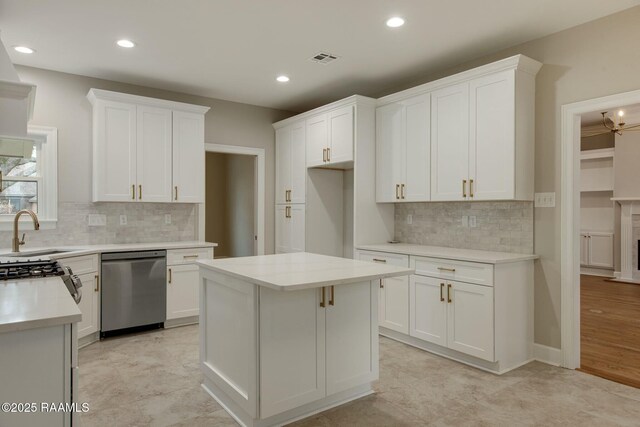 kitchen with light countertops, visible vents, stainless steel dishwasher, white cabinetry, and a sink