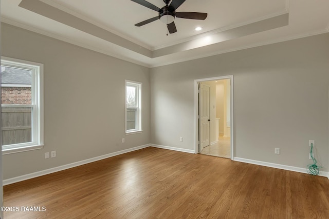 unfurnished room with a tray ceiling, baseboards, and wood finished floors