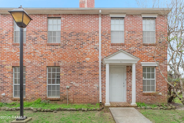 view of front of home featuring brick siding and a chimney