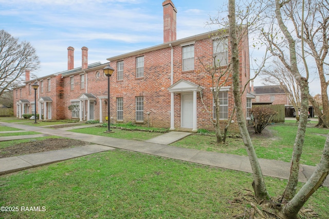 multi unit property featuring a front yard, brick siding, and a chimney