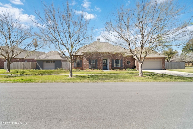 view of front of home featuring an attached garage, driveway, a front yard, and brick siding