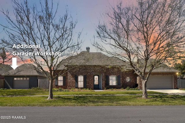 view of front of house featuring a garage, brick siding, and a yard