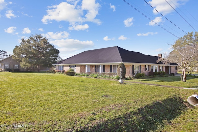 view of front of home featuring brick siding, a chimney, and a front yard