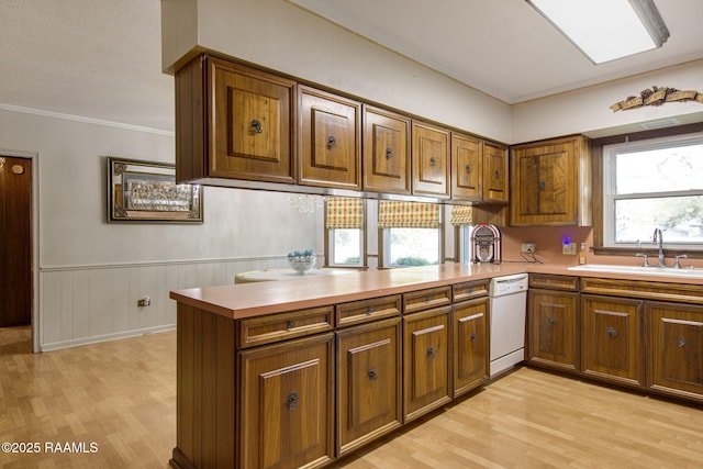 kitchen featuring dishwasher, brown cabinetry, and a sink