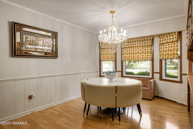 dining area with a wainscoted wall, wood finished floors, a chandelier, and ornamental molding