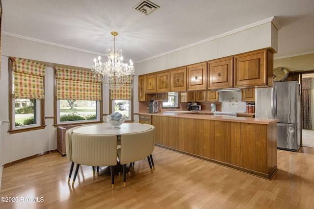 dining area featuring a notable chandelier, visible vents, crown molding, and light wood-type flooring