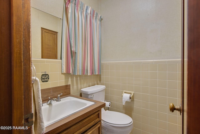 bathroom featuring toilet, tile walls, and vanity