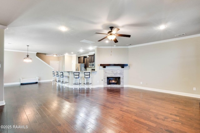 unfurnished living room with dark wood finished floors, baseboards, a ceiling fan, and ornamental molding