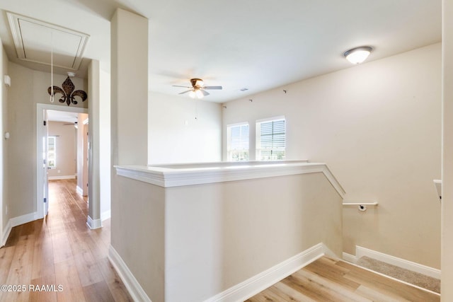 hallway with attic access, an upstairs landing, light wood-type flooring, and baseboards