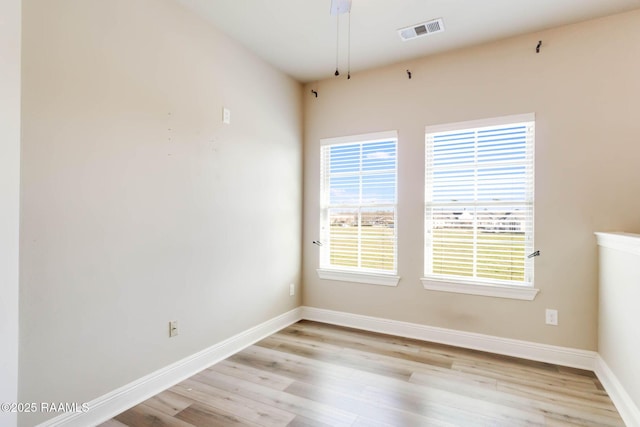 empty room featuring visible vents, a healthy amount of sunlight, baseboards, and light wood-style floors