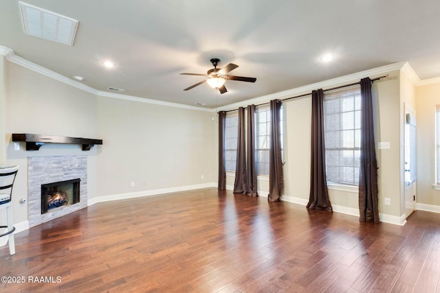 unfurnished living room featuring visible vents, ornamental molding, wood finished floors, a stone fireplace, and baseboards