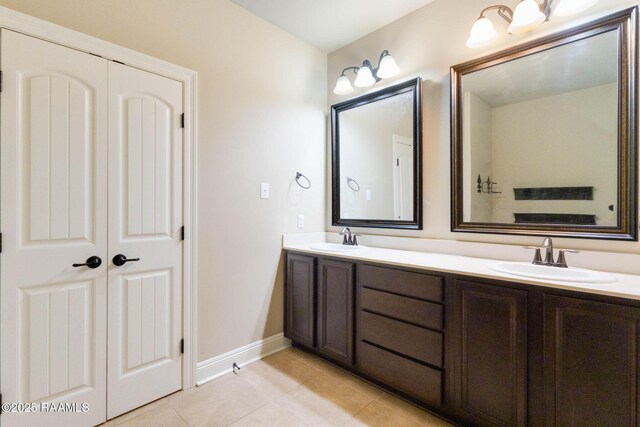 full bathroom with a sink, baseboards, double vanity, and tile patterned flooring