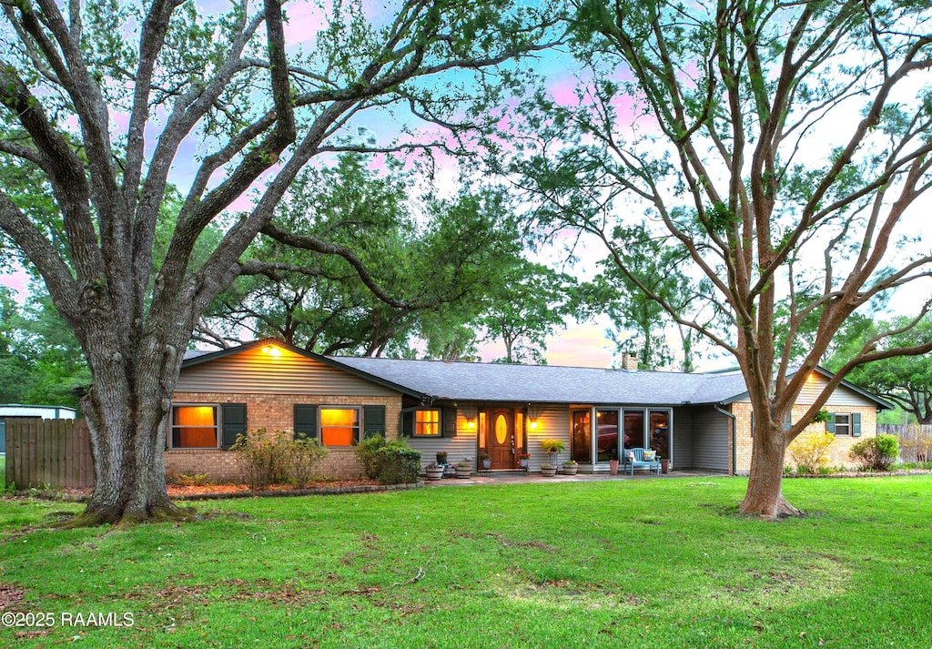 single story home with a chimney, brick siding, a patio, and a front yard