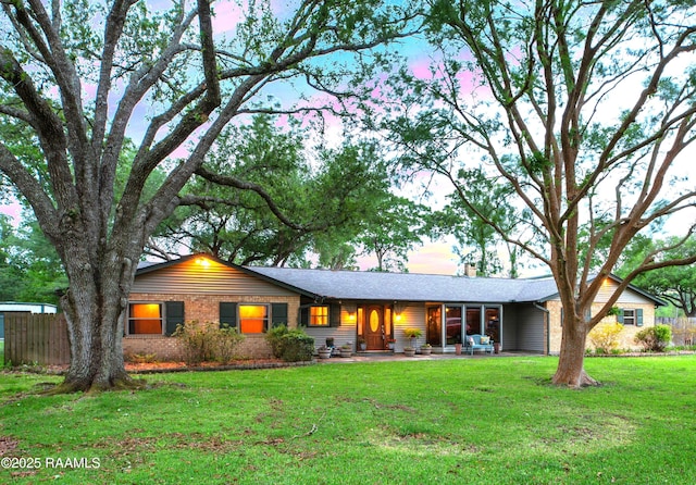 single story home with a chimney, brick siding, a patio, and a front yard