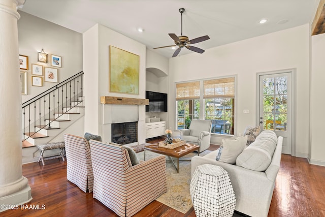 living room featuring recessed lighting, a fireplace, wood finished floors, a ceiling fan, and decorative columns