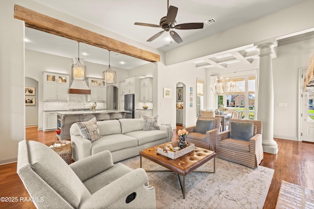 living room with baseboards, visible vents, arched walkways, wood finished floors, and beam ceiling