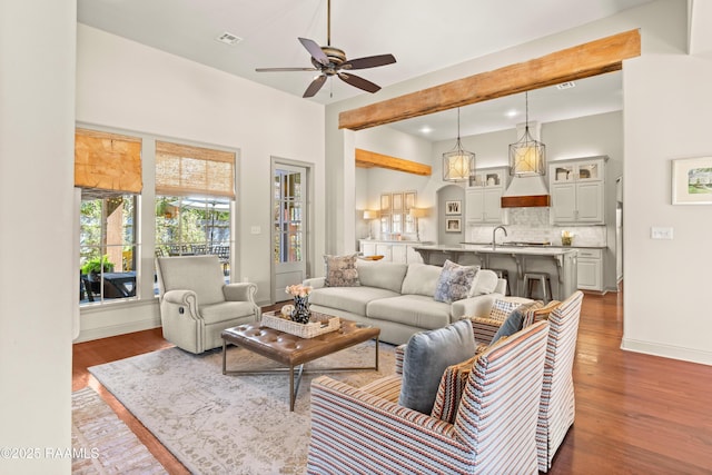 living area with dark wood-style floors, visible vents, a ceiling fan, and baseboards