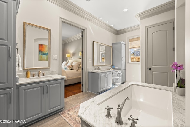 full bath featuring ornamental molding, two vanities, a sink, and a bath