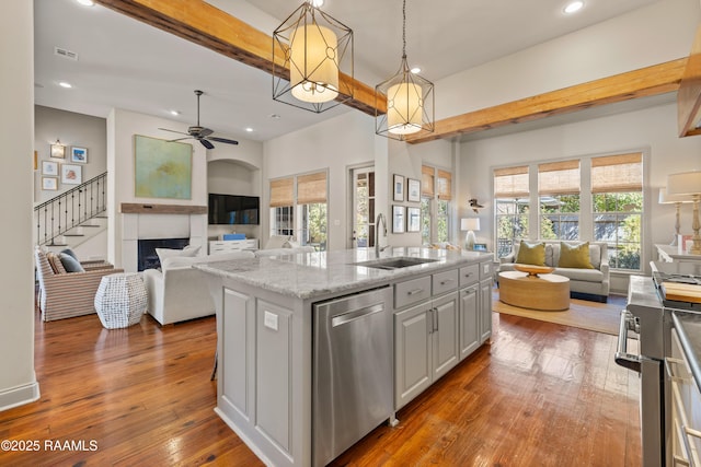 kitchen featuring a sink, hardwood / wood-style flooring, open floor plan, and stainless steel dishwasher