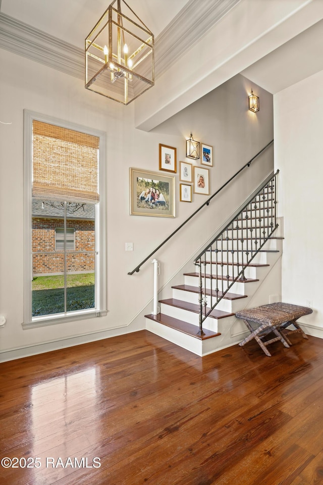 staircase featuring hardwood / wood-style flooring, a chandelier, and crown molding