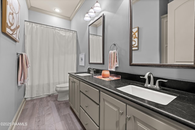 full bath with wood finished floors, double vanity, ornamental molding, and a sink