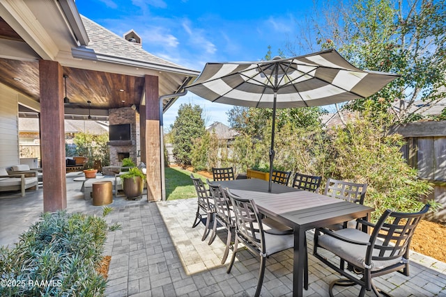 view of patio / terrace featuring an outdoor stone fireplace, fence, and outdoor dining area