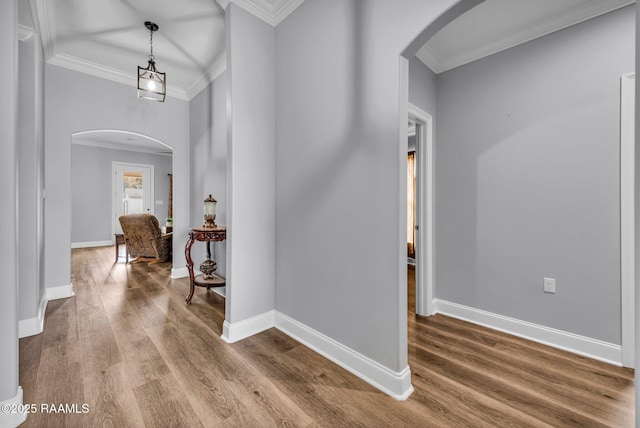 interior space featuring arched walkways, crown molding, baseboards, and wood finished floors