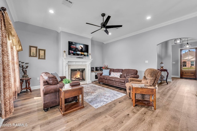 living room featuring light wood-type flooring, arched walkways, and ornamental molding