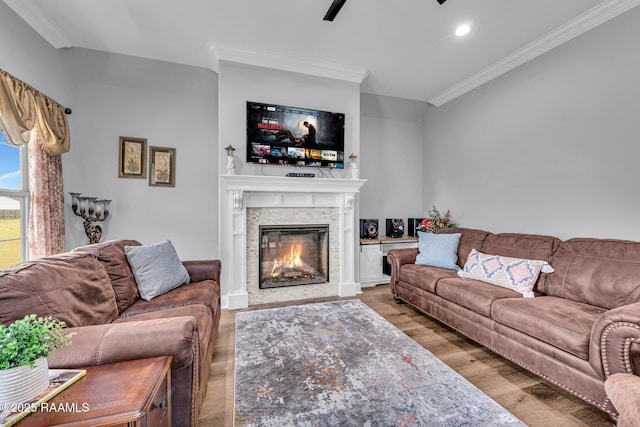 living area with recessed lighting, ornamental molding, wood finished floors, and a glass covered fireplace