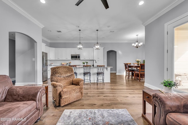 living room featuring arched walkways, crown molding, baseboards, and wood finished floors