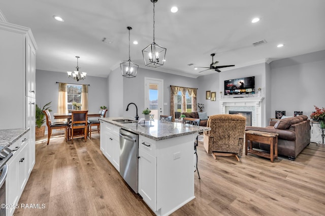 kitchen with a sink, visible vents, appliances with stainless steel finishes, light wood finished floors, and a glass covered fireplace