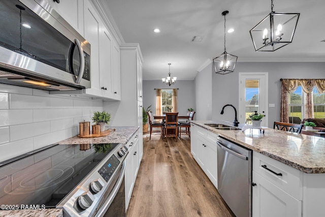 kitchen featuring light wood-style flooring, stainless steel appliances, a sink, decorative backsplash, and crown molding