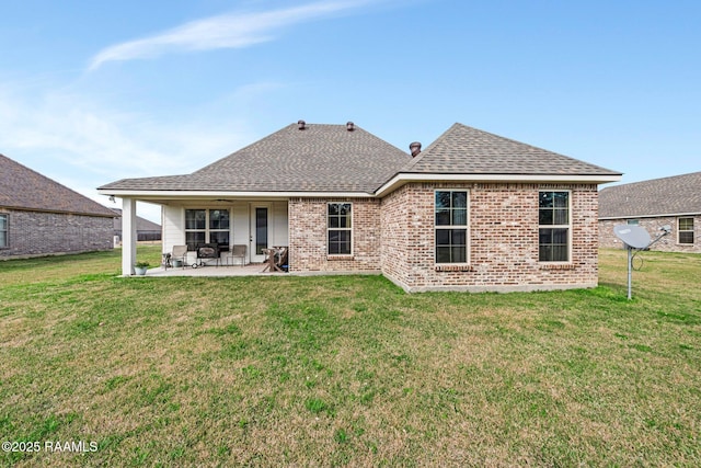 back of house with a patio area, a shingled roof, brick siding, and a yard