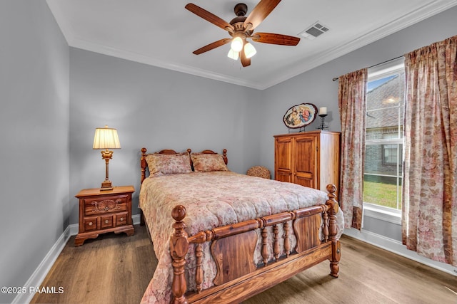 bedroom featuring ornamental molding, visible vents, baseboards, and wood finished floors