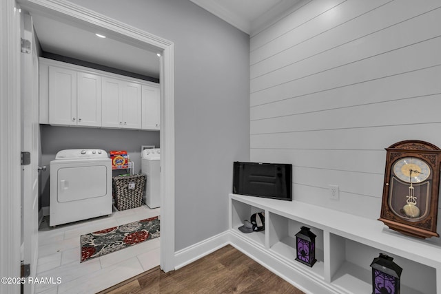 washroom with baseboards, washer and dryer, ornamental molding, cabinet space, and dark wood-style floors