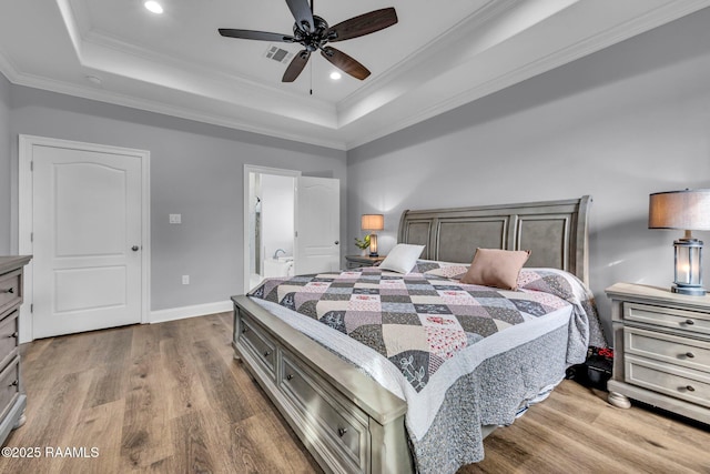 bedroom featuring ornamental molding, a tray ceiling, and wood finished floors