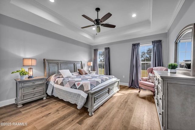 bedroom with crown molding, a raised ceiling, a ceiling fan, wood finished floors, and baseboards