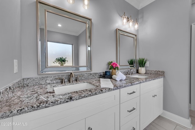 bathroom with double vanity, baseboards, ornamental molding, and a sink