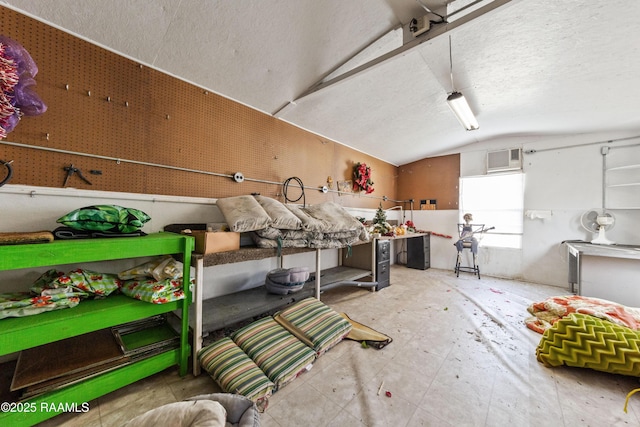 interior space with vaulted ceiling, a wall mounted air conditioner, and a textured ceiling