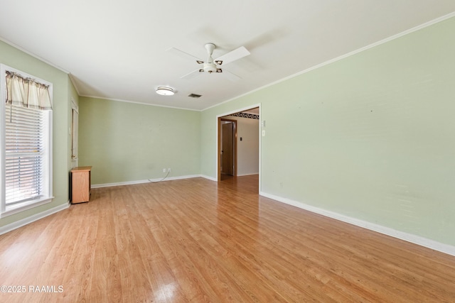 empty room with visible vents, a ceiling fan, light wood-style floors, crown molding, and baseboards