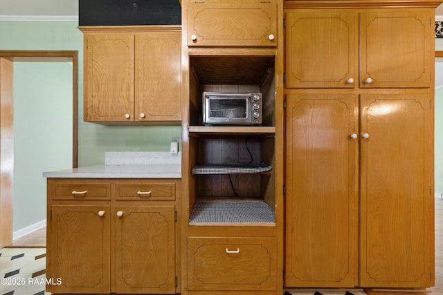 kitchen featuring a toaster, crown molding, light countertops, and baseboards