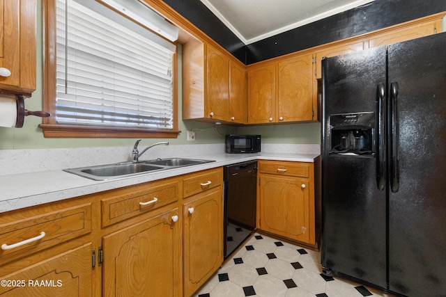 kitchen with brown cabinets, black appliances, a sink, light countertops, and light floors