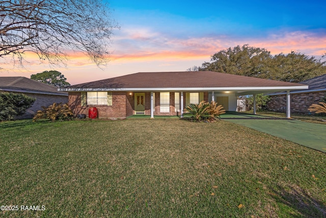 single story home featuring brick siding, driveway, a carport, and a front yard