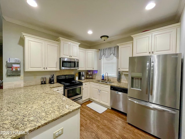 kitchen with stainless steel appliances, a sink, light wood-style flooring, and crown molding