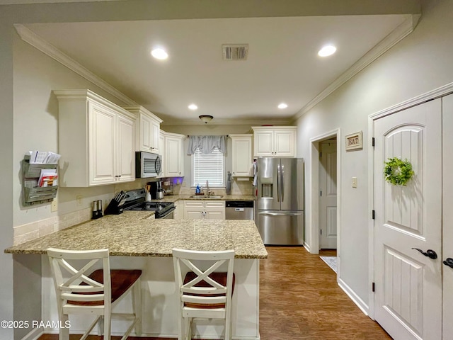 kitchen featuring visible vents, a peninsula, stainless steel appliances, crown molding, and a sink