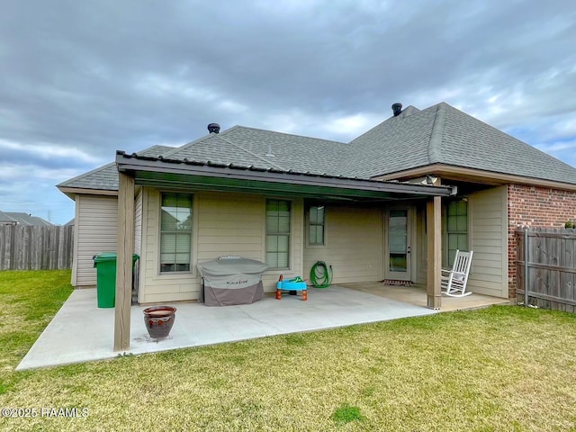 back of house with a shingled roof, a lawn, a patio, and fence