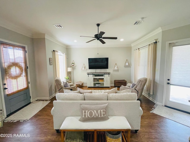 living room featuring dark wood-style flooring, visible vents, and crown molding