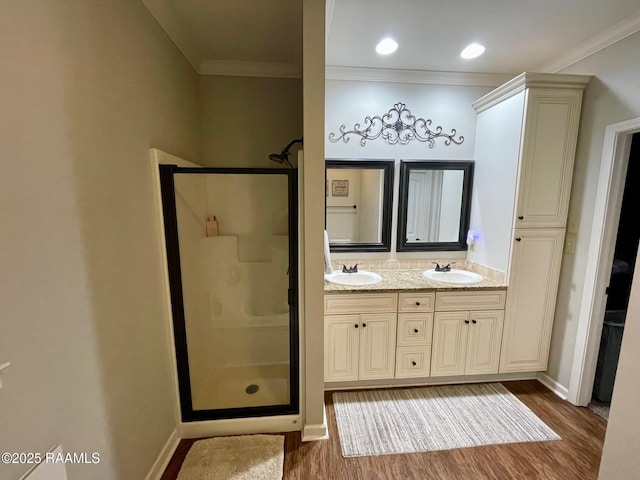 bathroom with crown molding, a sink, a shower stall, and wood finished floors