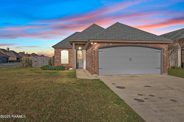 french country home featuring a front lawn, concrete driveway, a shingled roof, a garage, and brick siding